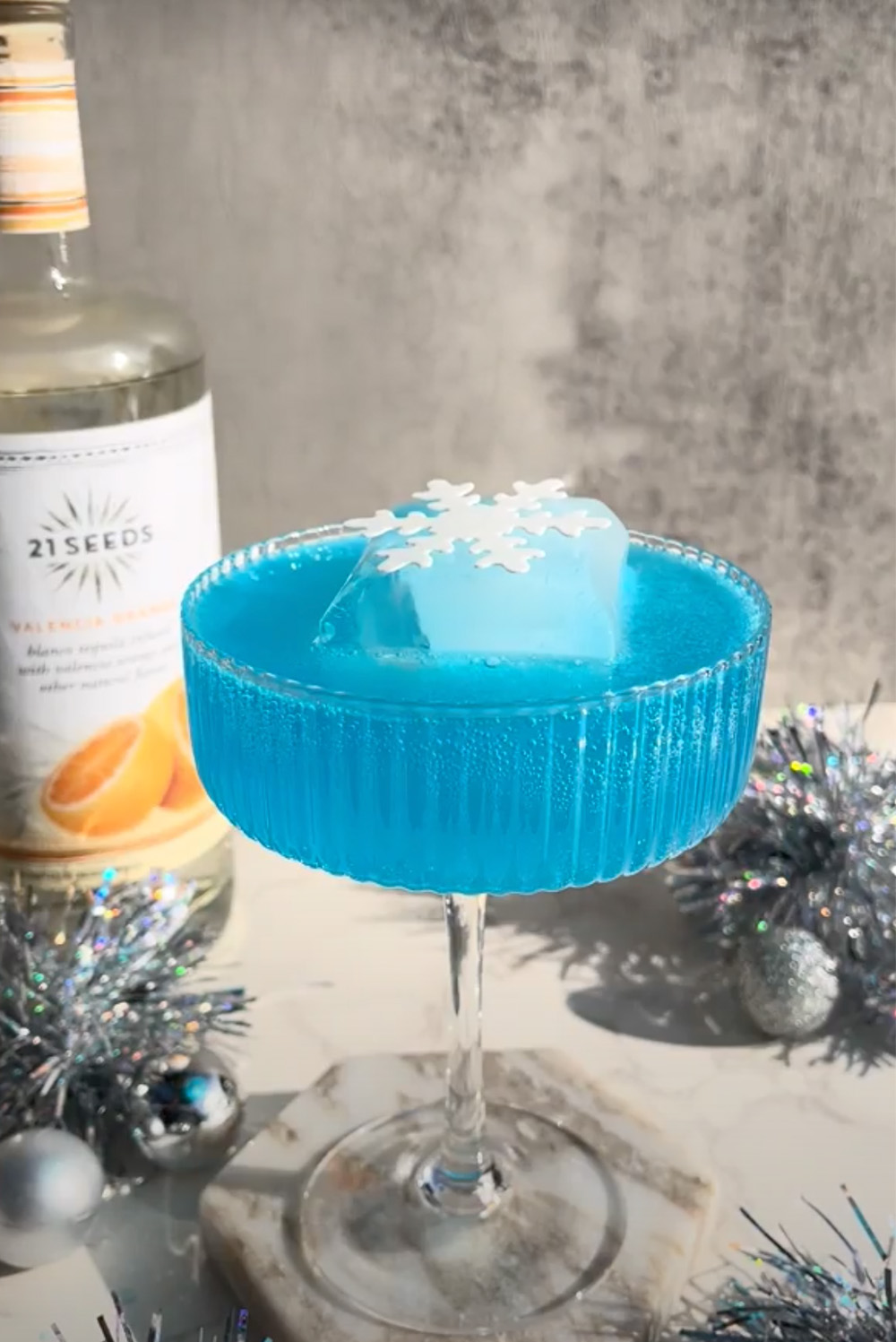 A Frostbite Seed + Soda cocktail adorned with delicate snowflakes on its surface.