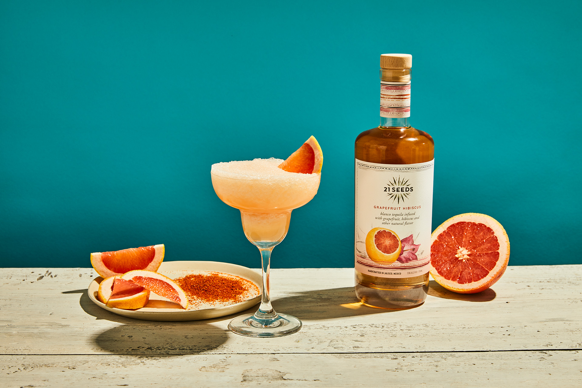 A frozen paloma cocktail in front of a bottle of 21Seeds Grapefruit Hibiscus Infused Tequila