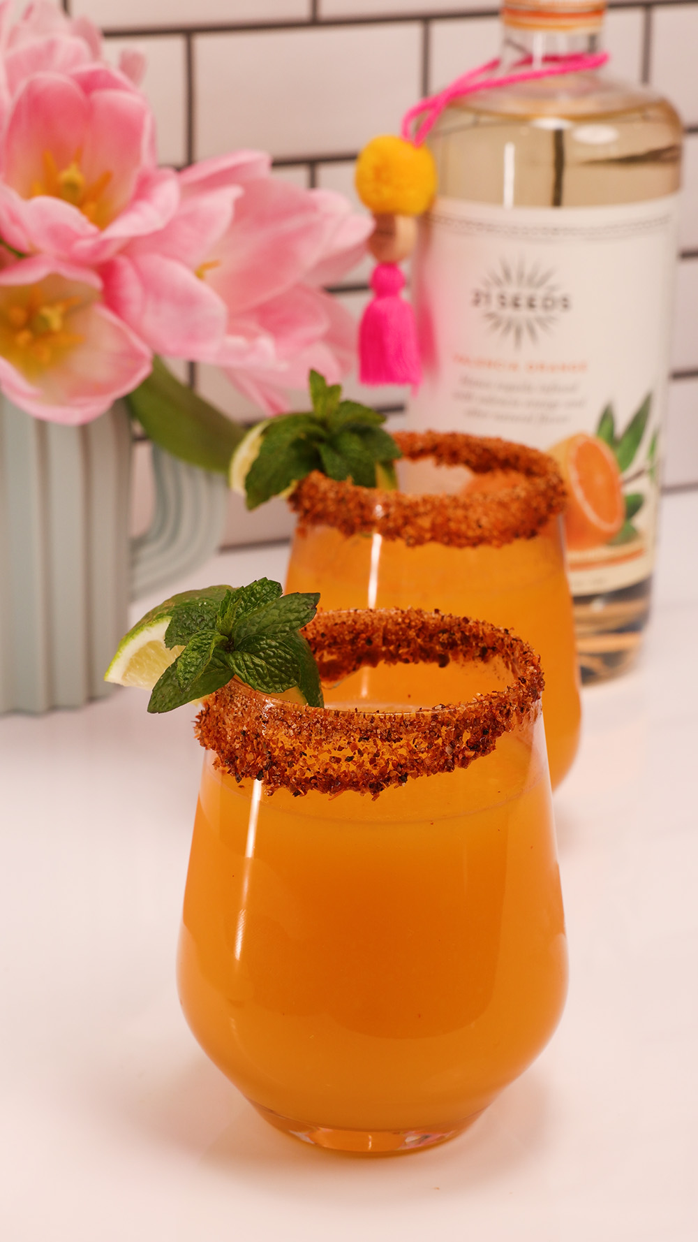Two frozen orange cocktails in front of a bottle of 21Seeds Valenca Orange Infused Tequila
